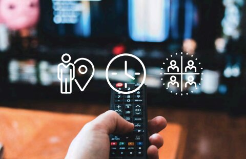 Hand pointing a TV remote at a streaming TV, with targeting icons for audience, day-parting, and demographics